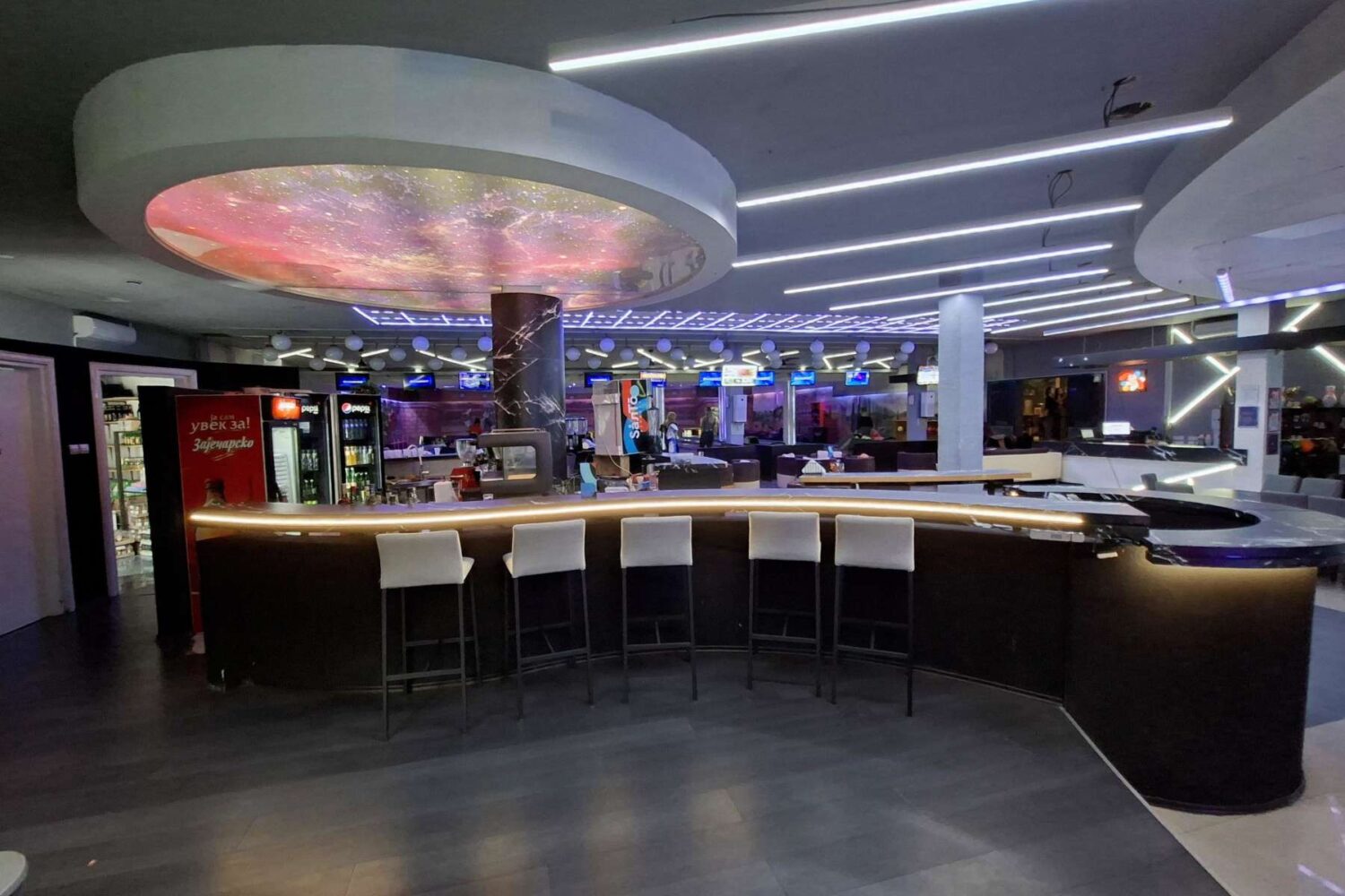 Moderan, dobro osvetljen šank i bar sa raznovrsnim pićima, visokim stolicama i osobljem, u Colosseum Bowlin centru.