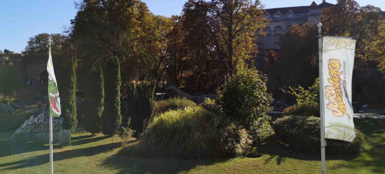 Panoramski pogled na Dino park na Kalemegdanu sa nekoliko figura dinosaurusa i stazama, sunčan dan.