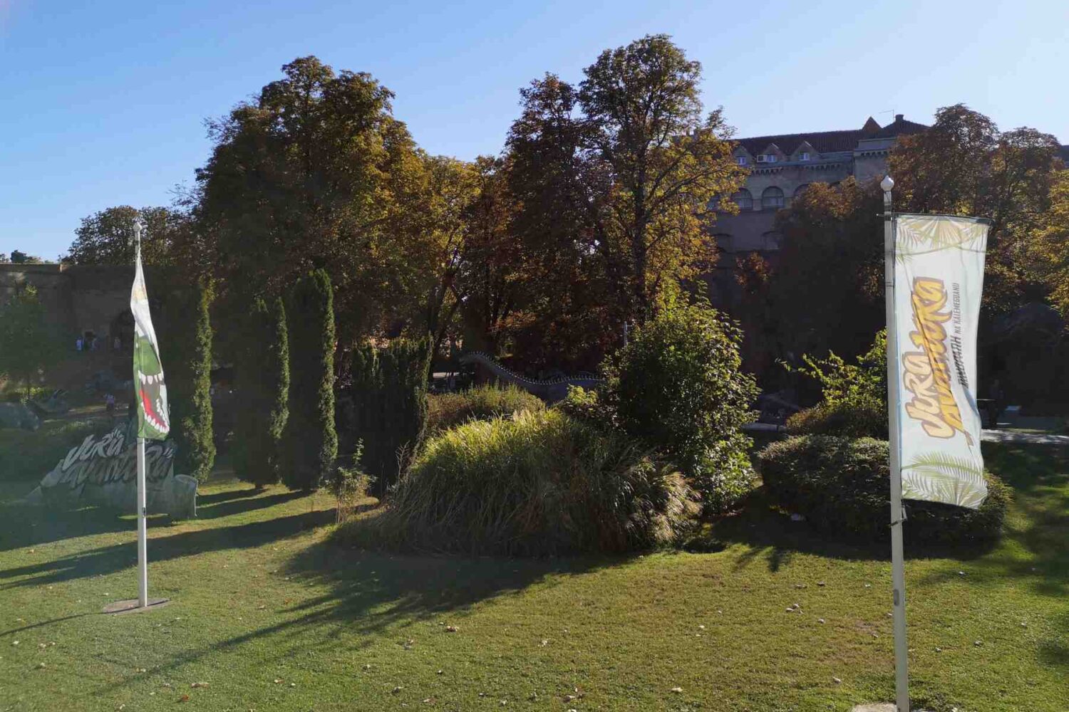 Panoramski pogled na Dino park na Kalemegdanu sa nekoliko figura dinosaurusa i stazama, sunčan dan.