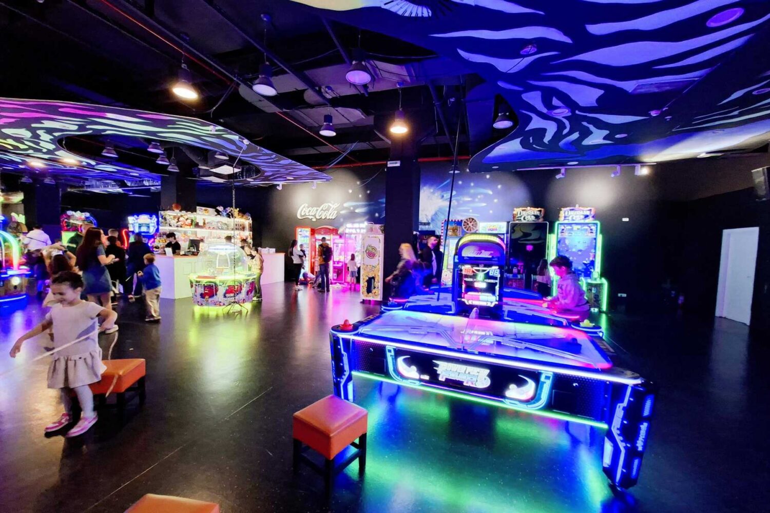 Dinamičan, blago osvetljen široki kadar Futurama centra, prikazuje grupe ljudi, tinejdžera i porodica kako igraju različite arkadne igre.