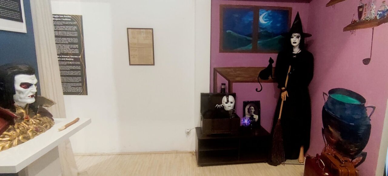 Prikaz unutrašnjosti muzejske sobe sa figurom veštice i rekvizitima, tematska postavka.