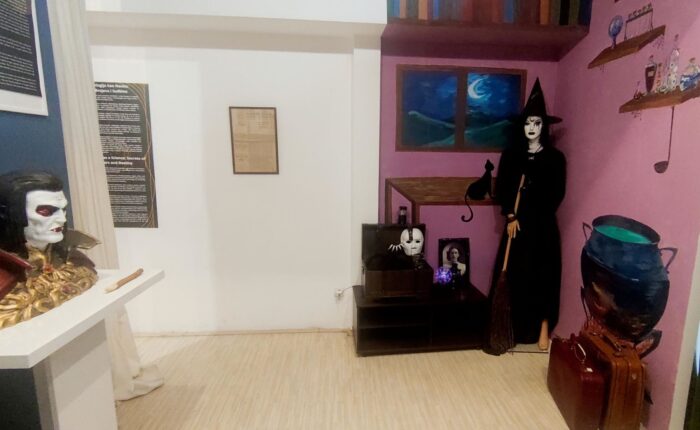 Prikaz unutrašnjosti muzejske sobe sa figurom veštice i rekvizitima, tematska postavka.