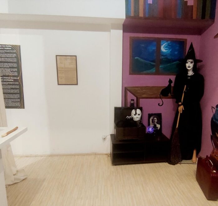 Prikaz unutrašnjosti muzejske sobe sa figurom veštice i rekvizitima, tematska postavka.