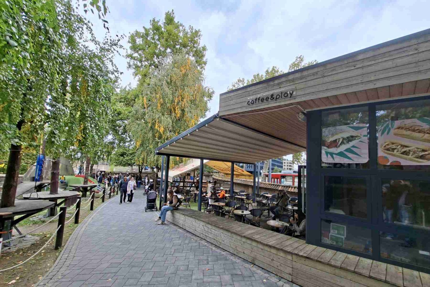 Kafić ili prostor za odmor sa stolovima i stolicama, smešten pored ograde ili kaveza u Mini Zoo vrtu.
