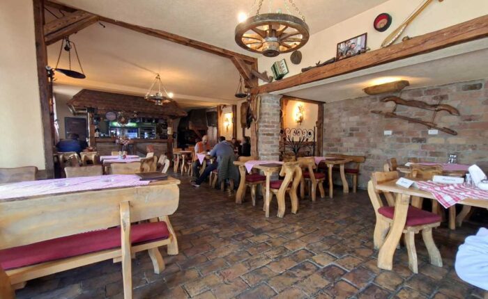 Unutrašnjost restorana Konoba pod Avalom sa stolovima i šankom u etno ambijentu