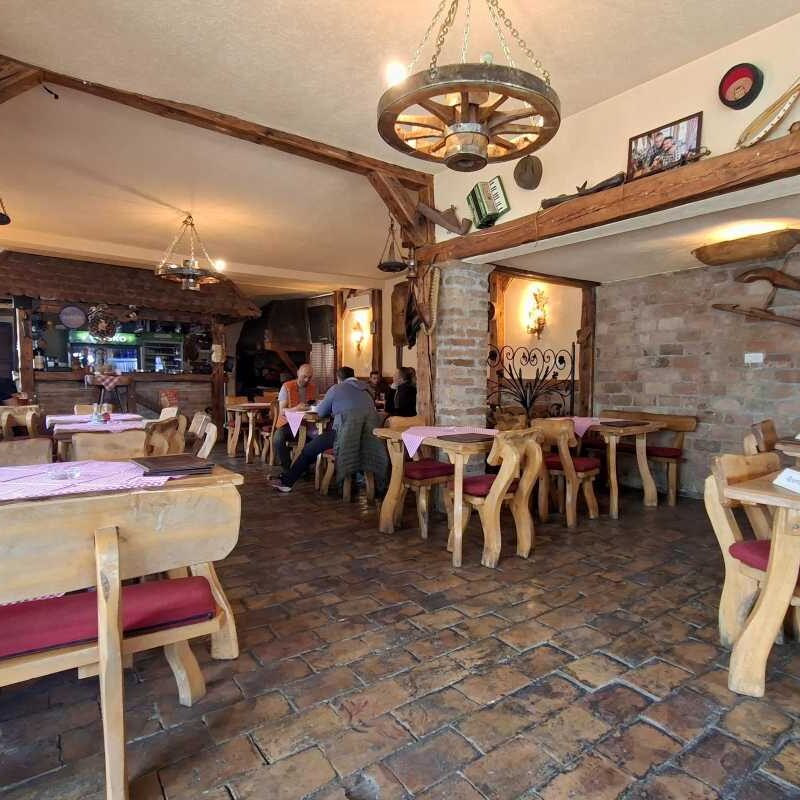 Unutrašnjost restorana Konoba pod Avalom sa stolovima i šankom u etno ambijentu