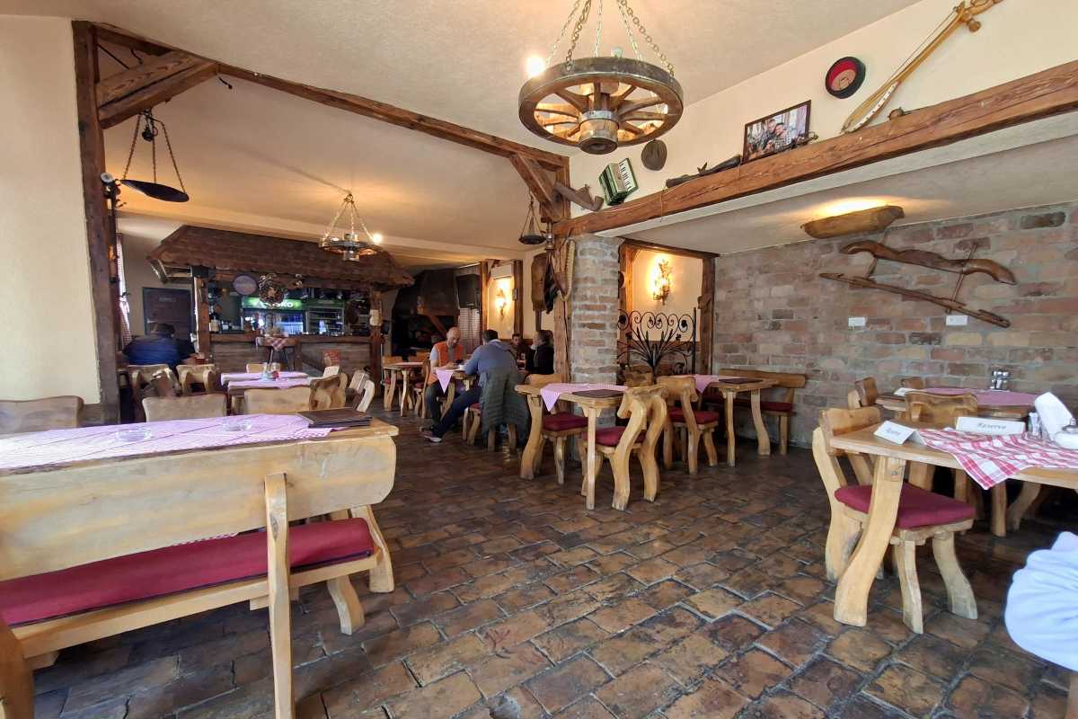 Unutrašnjost restorana Konoba pod Avalom sa stolovima i šankom u etno ambijentu